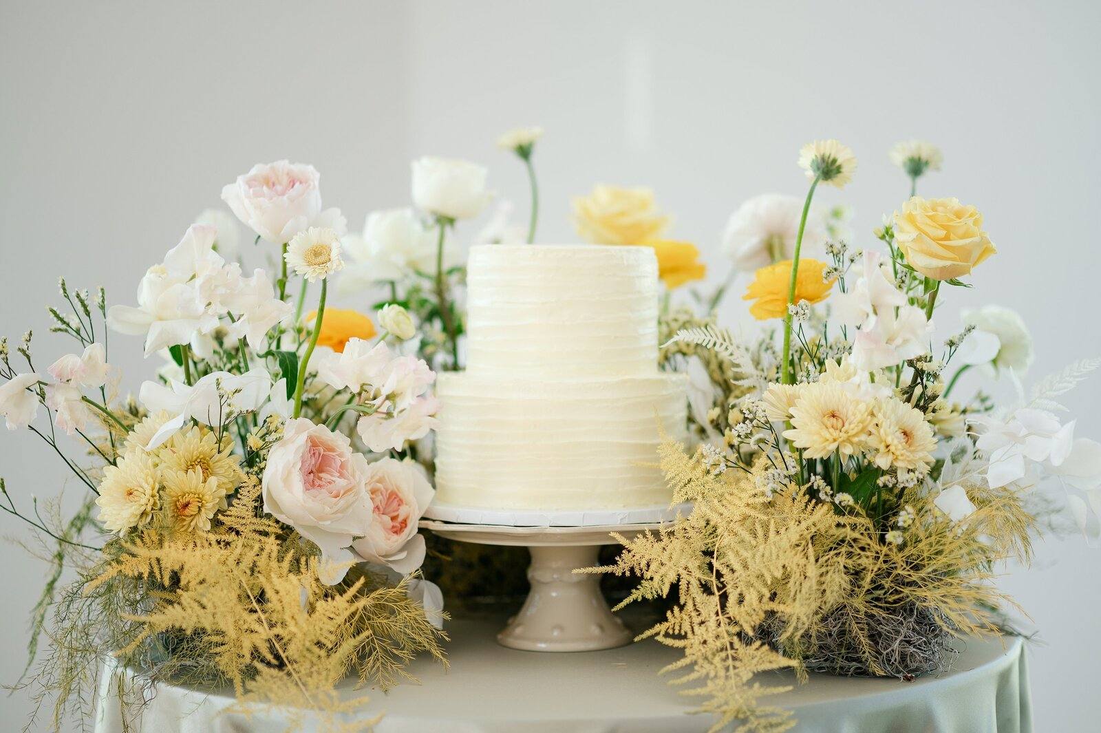A wedding cake surrounded by garden flowers