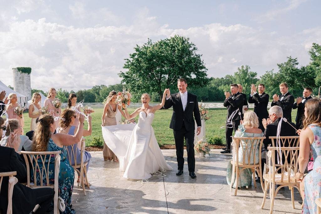 Guests cheering as a newly married couple walks back up the aisle
